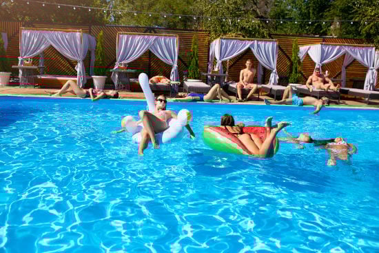 Pergolas aménagées avec transats et  rideaux en bordure de piscine