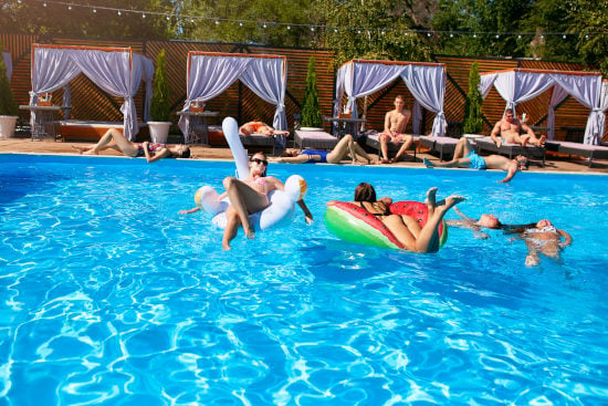 Pergolas aménagées avec transats et  rideaux en bordure de piscine