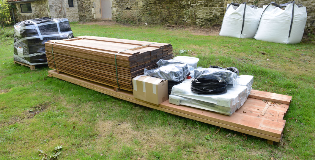 Terrasse bois stockée à plat sur palette, prête à être posée